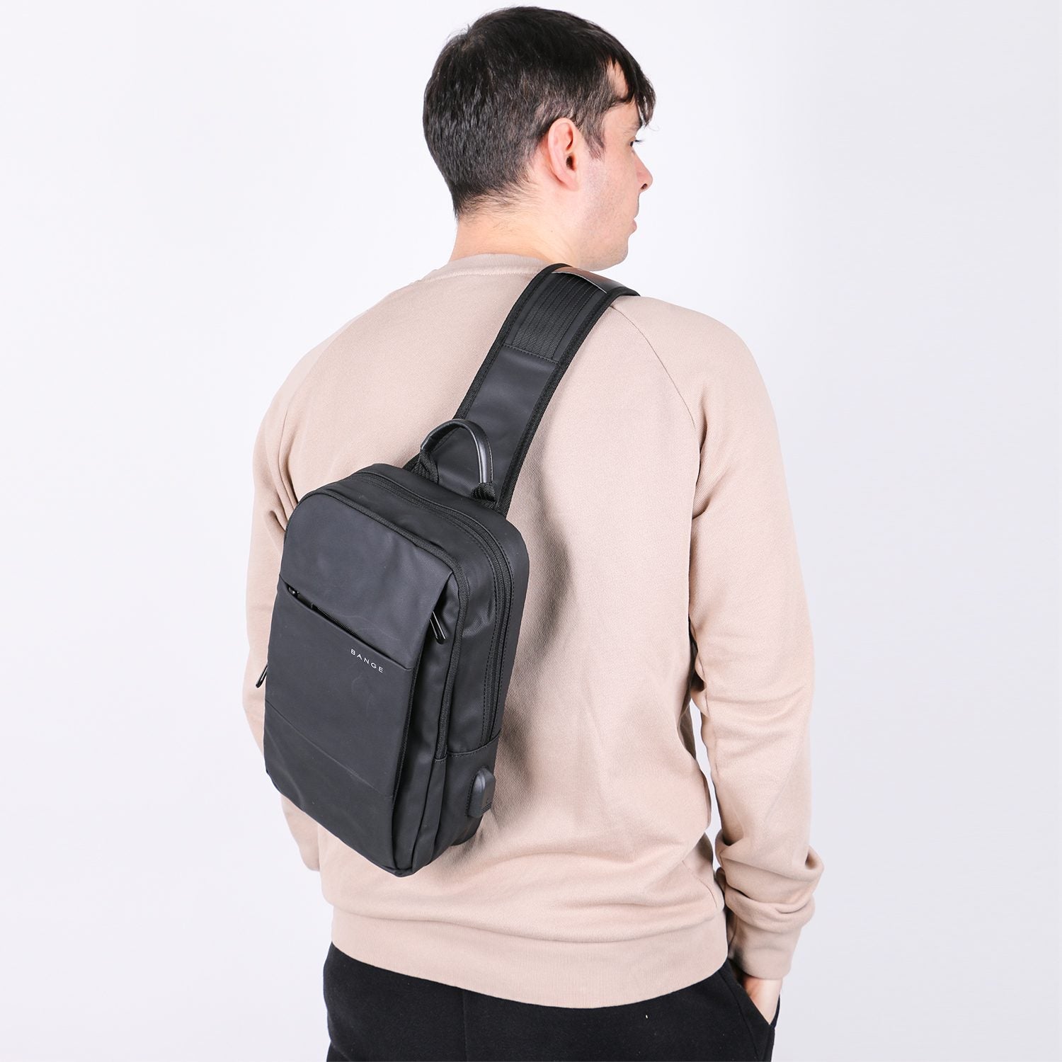 Person wearing a black sling bag on a plain background